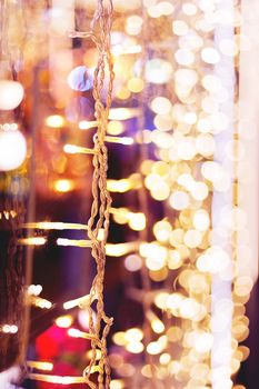 Defocused night street lights, blurred colorful bokeh background. Holiday colorful lanterns and light bulbs garlands.