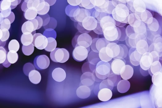 Defocused night street lights, blurred colorful bokeh background. Holiday colorful lanterns and light bulbs garlands.