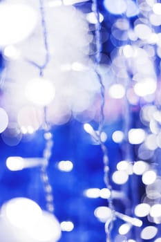 Defocused night street lights, blurred colorful bokeh background. Holiday colorful lanterns and light bulbs garlands.