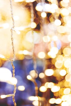 Defocused night street lights, blurred colorful bokeh background. Holiday colorful lanterns and light bulbs garlands.