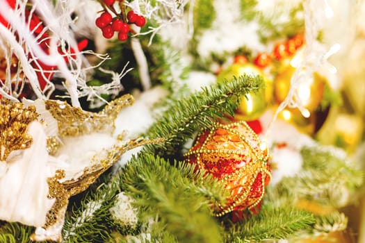 Christmas and New Year background with fir tree branches and decorations - light bulbs, berries, golden snowflakes.