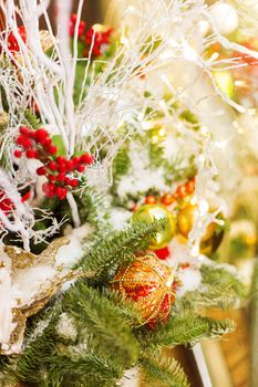 Christmas and New Year background with fir tree branches and decorations - light bulbs, berries, golden snowflakes.