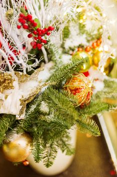 Christmas and New Year background with fir tree branches and decorations - light bulbs, berries, golden snowflakes.