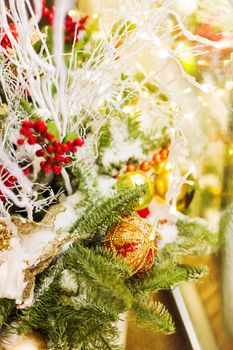 Christmas and New Year background with fir tree branches and decorations - light bulbs, berries, golden snowflakes.