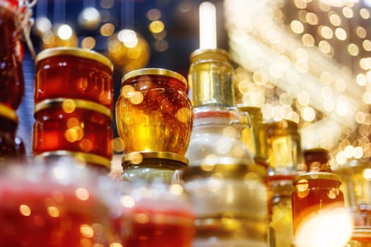 Holiday fair. Jars of honey glowing in garlands of lighting bulbs.