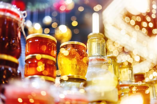 Holiday fair. Jars of honey glowing in garlands of lighting bulbs.