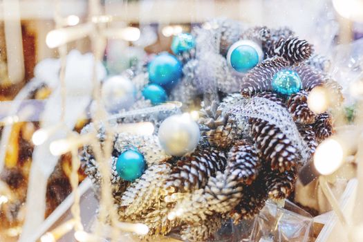 Christmas wreath made with pine and fir cones, bright blue balls. Hand made New Year decoration with light bulbs.