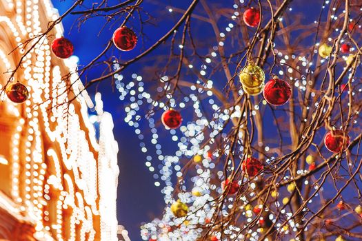 Streets of Moscow decorated for New Year and Christmas celebration. Tree with bright red and yellow balls. GUM (Main Department Store) building with light bulbs. Russia.