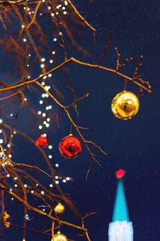 Streets of Moscow decorated for New Year and Christmas celebration. Tree with bright red and yellow balls. The St.Nicholas (Nikolskaya) tower of Kremlin on the background. Russia.