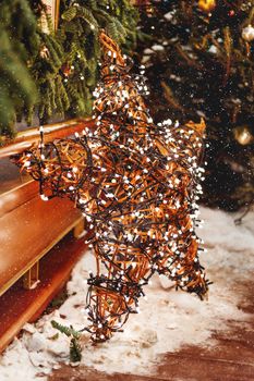 Christmas and New Year background with fir trees and bright decorative star - outdoor decoration made of willow branches with light bulbs garland.