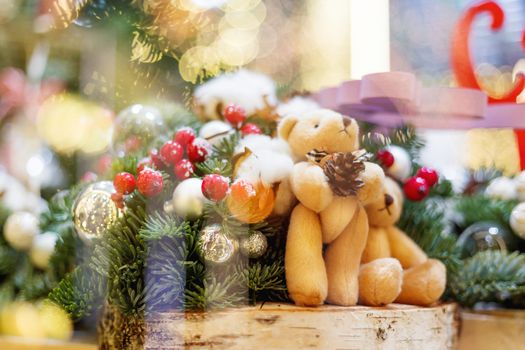 Christmas and New Year background with fir trees and toy bears - decoration made of branches with light bulbs and bright balls.