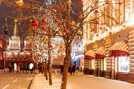 Streets of Moscow decorated for New Year and Christmas celebration. Tree with bright red and yellow balls. Buildings with light bulbs.