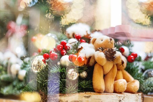 Christmas and New Year background with fir trees and toy bears - decoration made of branches with light bulbs and bright balls.