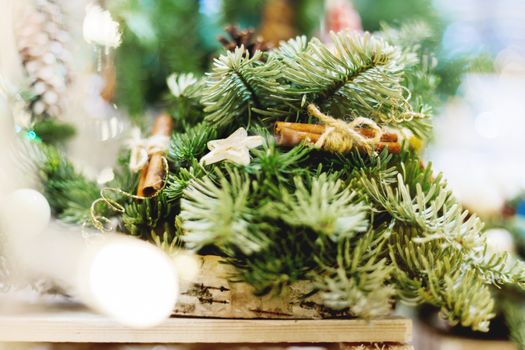 Christmas wreath made with pine and fir branches, cinnamon and wooden stars. Hand made New Year decoration with light bulbs.
