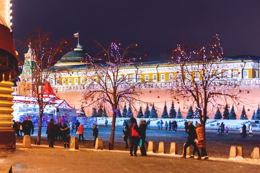 Streets of Moscow decorated for New Year and Christmas celebration. Tree with bright red and yellow balls. Buildings on Red Square with light bulbs.