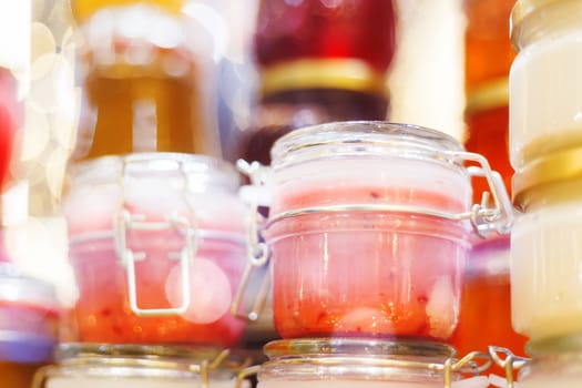 Holiday fair. Jars of creamy honey with berries glowing in garlands of lighting bulbs.