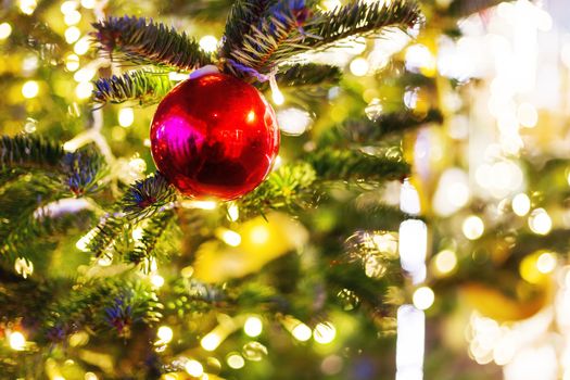 Christmas and New Year background with fir tree branches and decorations - light bulbs and bright red ball.