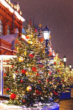 Streets in the historical center of Moscow decorated for New Year and Christmas celebration. Fir trees with bright red and yellow balls and light bulbs. Russia.