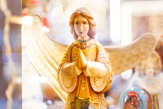 Wooden carved angel, Christmas holiday decoration. Bright light bulbs on background.