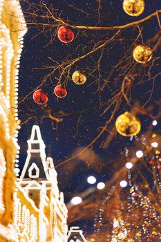 Streets of Moscow decorated for New Year and Christmas celebration. Tree with bright red and yellow balls. GUM (State Department Store) building with light bulbs. Russia.