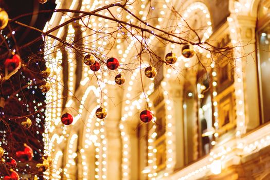 Streets of Moscow decorated for New Year and Christmas celebration. Tree with bright red and yellow balls. Buildings with light bulbs. Russia.