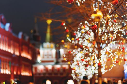 Streets of Moscow decorated for New Year and Christmas celebration. Tree with bright red and yellow balls. Buildings with light bulbs. Russia.