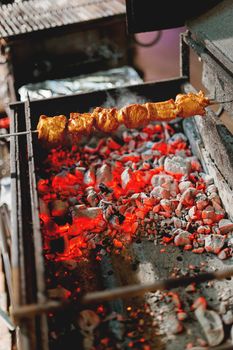 A barbecue skewer spinning on the grill. Fresh steaming meat BBQ. Street cart with grill.