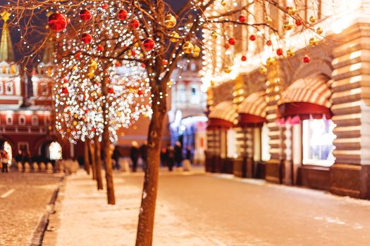 Streets of Moscow decorated for New Year and Christmas celebration. Tree with bright red and yellow balls. Buildings with light bulbs.