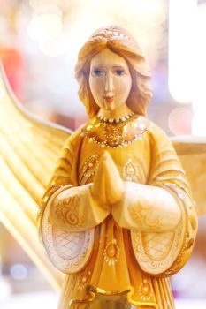 Wooden carved angel, Christmas holiday decoration. Bright light bulbs on background.