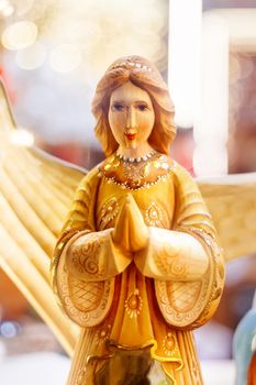Wooden carved angel, Christmas holiday decoration. Bright light bulbs on background.