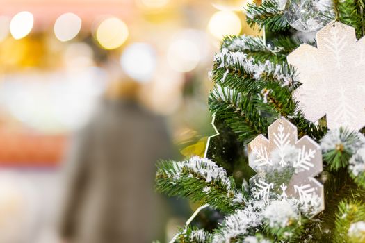 Fir tree decorated with shiny snow flakes and light bulbs for Christmas and New Year celebration.