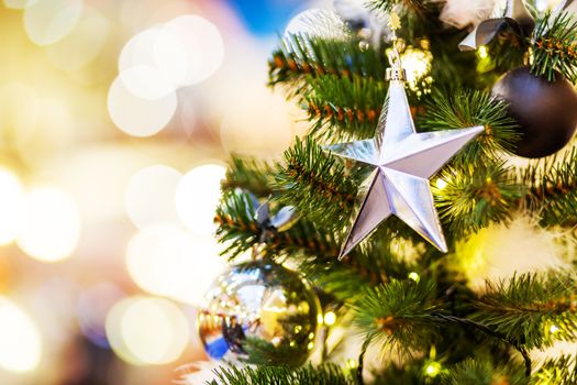 Fir tree decorated with shiny balls, star and light bulbs for Christmas and New Year celebration.