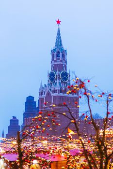 Red Square decorated for New Year and Christmas fair. Spasskaya tower upon trees decorated with light bulbs.