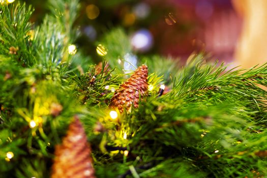 Pine tree decorated with cones and light bulbs for Christmas and New Year celebration. Natural winter background.