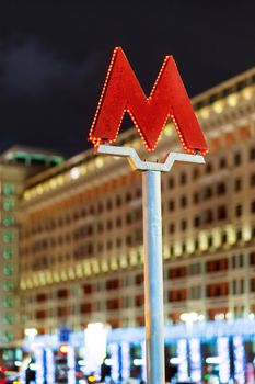 Red letter M - symbol of Moscow subway (metro). Street decorated with light bulbs for New Year and Christmas celebration. Winter evening. Russia.