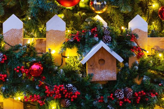 Christmas and New Year outdoor decorations - bird house with traditional fir tree wreaths.