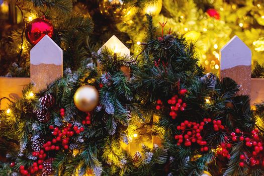 Christmas and New Year outdoor decorations - traditional fir tree wreaths with balls and berries on fence.