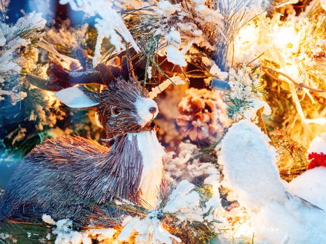 Christmas and New Year decorations with deer made of straw, light bulbs and fake snow.