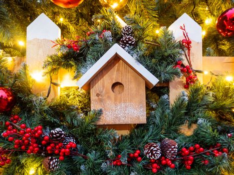Christmas and New Year outdoor decorations - bird house with traditional fir tree wreaths.