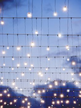 Light bulbs shine like stars on blue evening sky background. Outdoor decoration on Rozhdestvenka street for Christmas and New Year holidays celebration. Moscow, Russia.