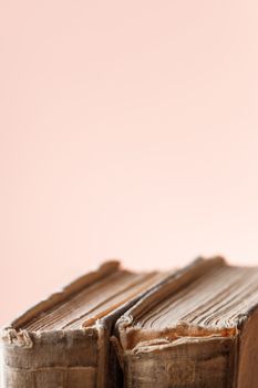 Banner with two old books. Books with shabby covers and ragged pages on light pink background with copy space.