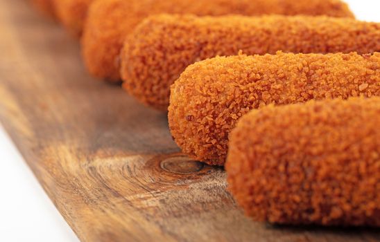 Brown crusty dutch kroketten on a serving tray, selective focus, isolated