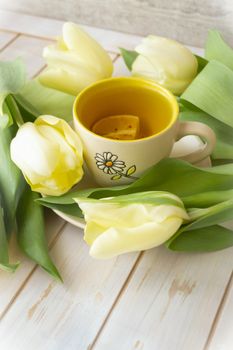 A mug with tea with yellow tulips. Women, mother, valentines day greeting card, vertical image