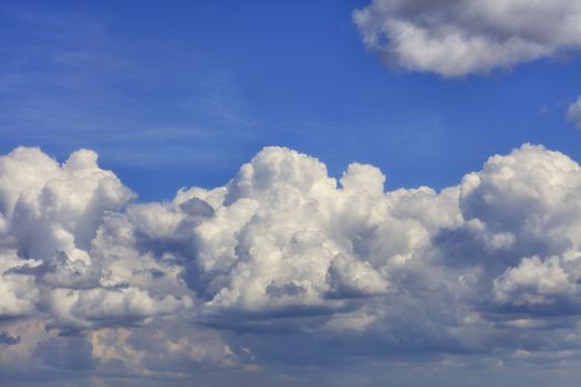 In the blue sky, a white-gray fluffy cloud gradually turns into a gray rainy cloud. Close-up.