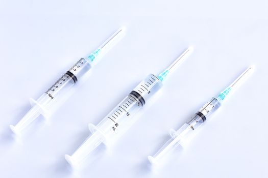 Three syringes of different capacity on a white table, prepared for injection in the hospital with copyspace for text..