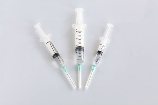 Three syringes of different capacity on the table in the hospital, prepared for injection, copyspace for the text below.