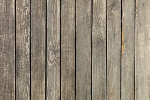 Weathered old gray wooden fence, vertical planks, close-up.