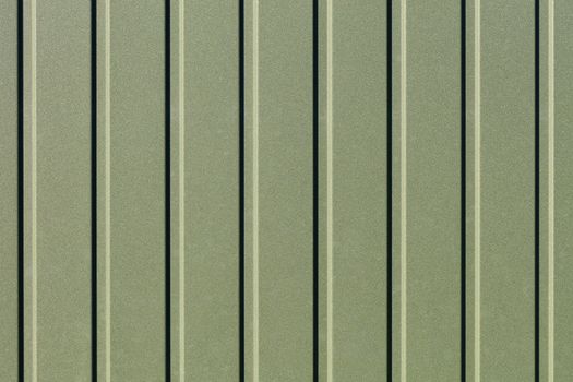 Greenery metallic fence made of corrugated steel sheet with vertical guides. Corrugated green iron sheet background close up.