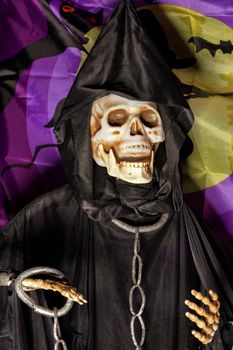 Halloween, doll Death in a black hoodie and a hood on the head with metal chains on the neck and arms.