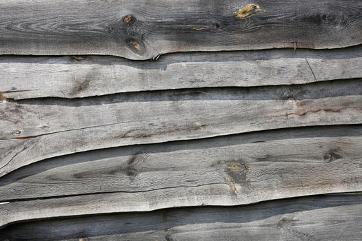 A wooden fence roughly cobbled together from weathered old gray boards horizontally.